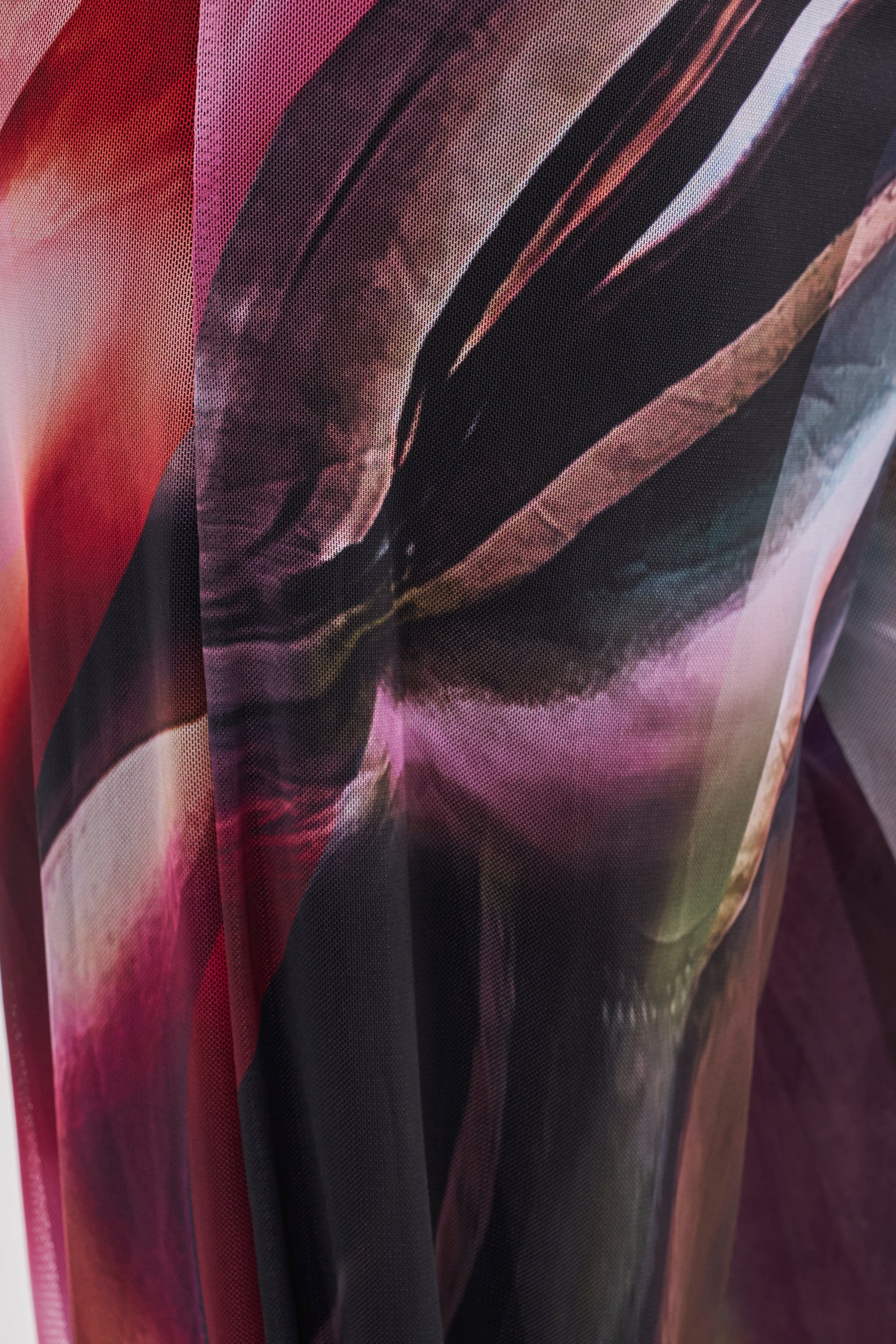 Abstract close-up of flowing fabric in red, pink, black, and white, with smooth curves and a soft, translucent look—evoking the multicolor swirl print of the MAIN CHARACTER ENERGY COWL NECK JUMPSUIT. 6