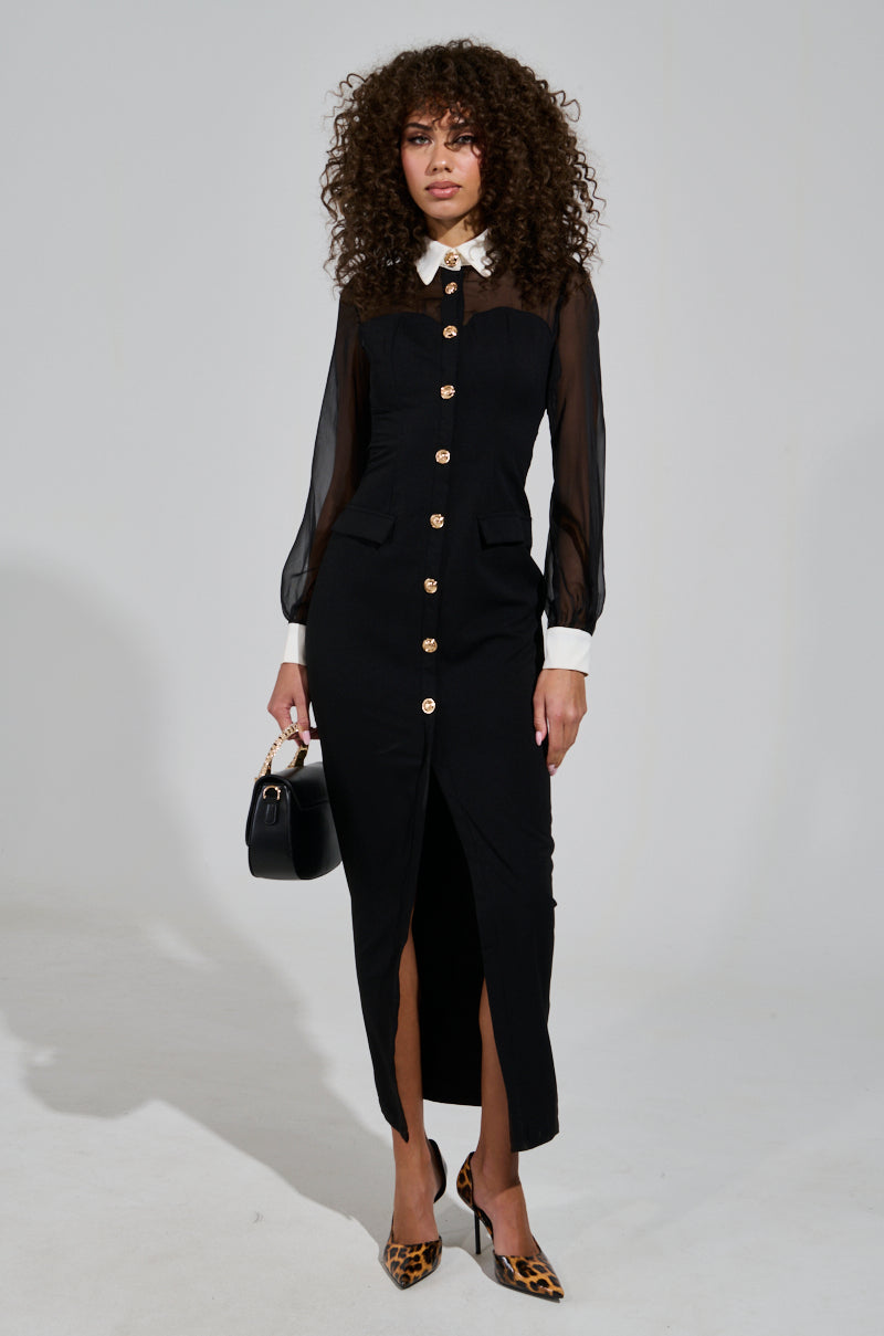 A woman with curly hair wears the "BUTTON UP BUTTER CUP COLLARED MAXI DRESS," which features sheer sleeves and a sheer mesh bodice. She completes her look with a small black handbag and leopard print heels, standing gracefully against a plain background.