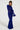 A person stands confidently in the MY GOOD SIDE LEOPARD MESH MAXI DRESS IN BLUE, featuring a long, sheer design with long sleeves. They have braided hair and are posing on a plain white background, looking directly at the camera.