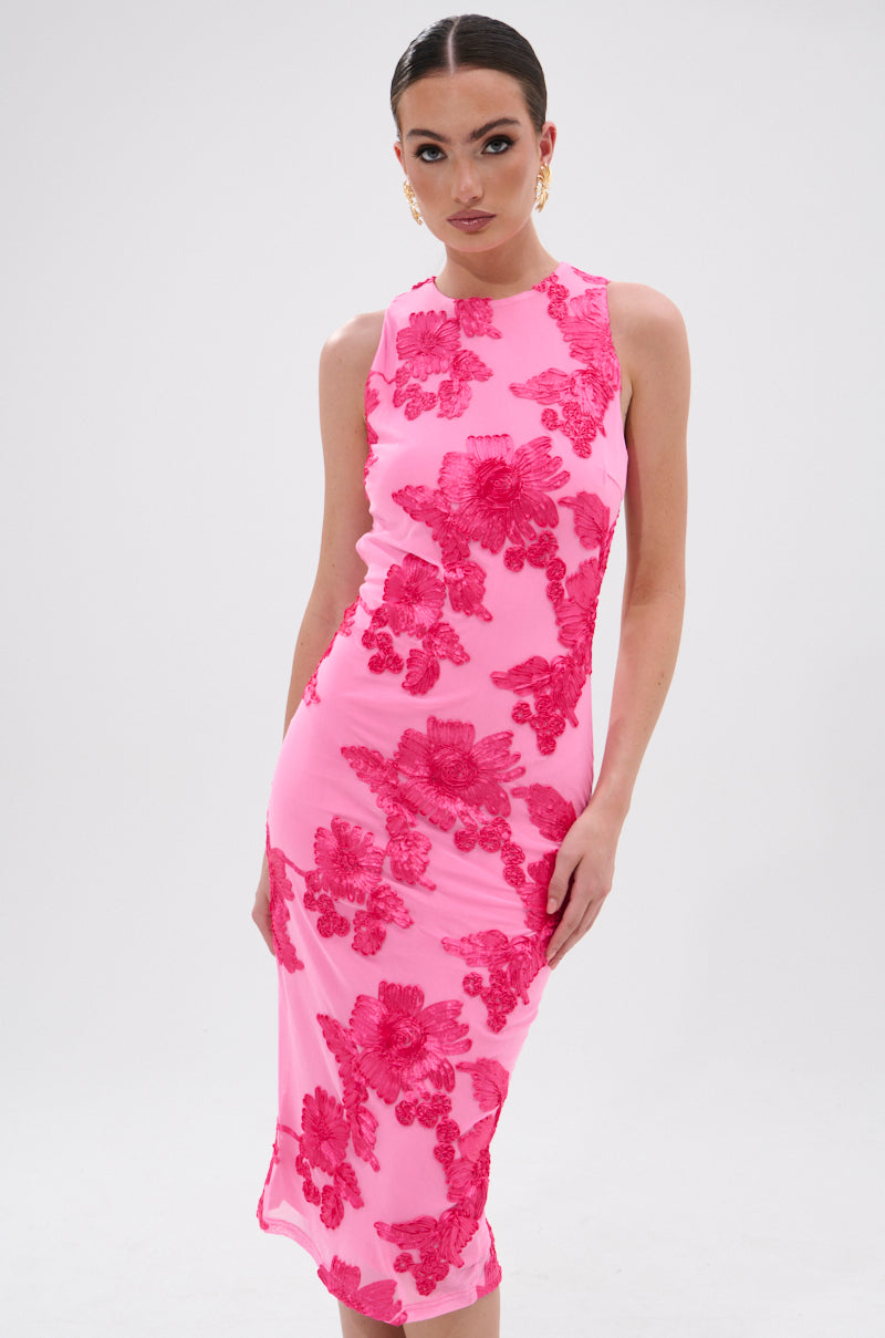 A woman wears the TIMELESS FLORAL MESH MIDI DRESS—a sleeveless, fitted pink midi dress with bold red floral appliqués. Her hair is slicked back, gold earrings shine, and she poses against a plain white background. 2