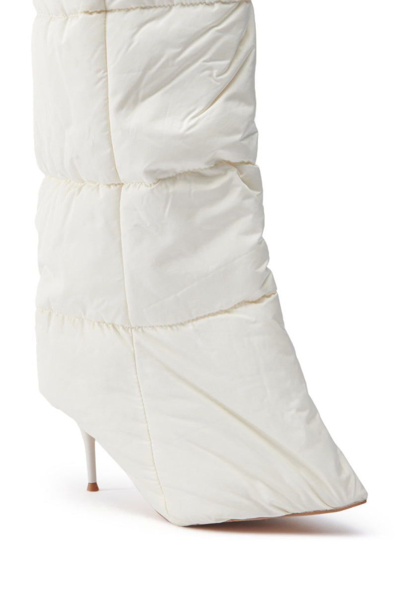 A close-up of the DREAMSICLE CREAM PUFFER STILETTO BOOT reveals its white quilted design with a high heel. This sculptural silhouette features a puffy, padded texture similar to a down jacket and showcases a pointed toe design against a crisp white backdrop.