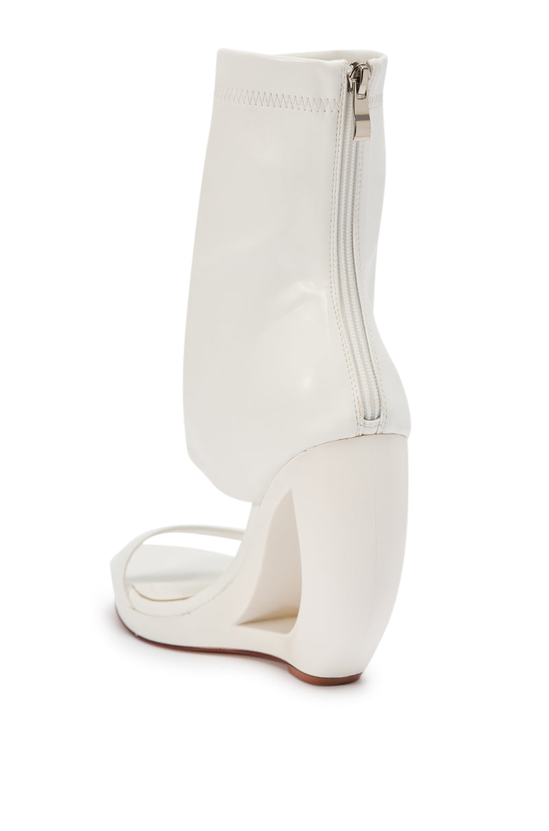 The AKIRA GOLD DUMISANI WHITE WEDGE OPEN TOE BOOTIE features a modern, minimalist white design with a sculptural curved wedge heel, open toe, boot-style upper, and a convenient back zipper closure.