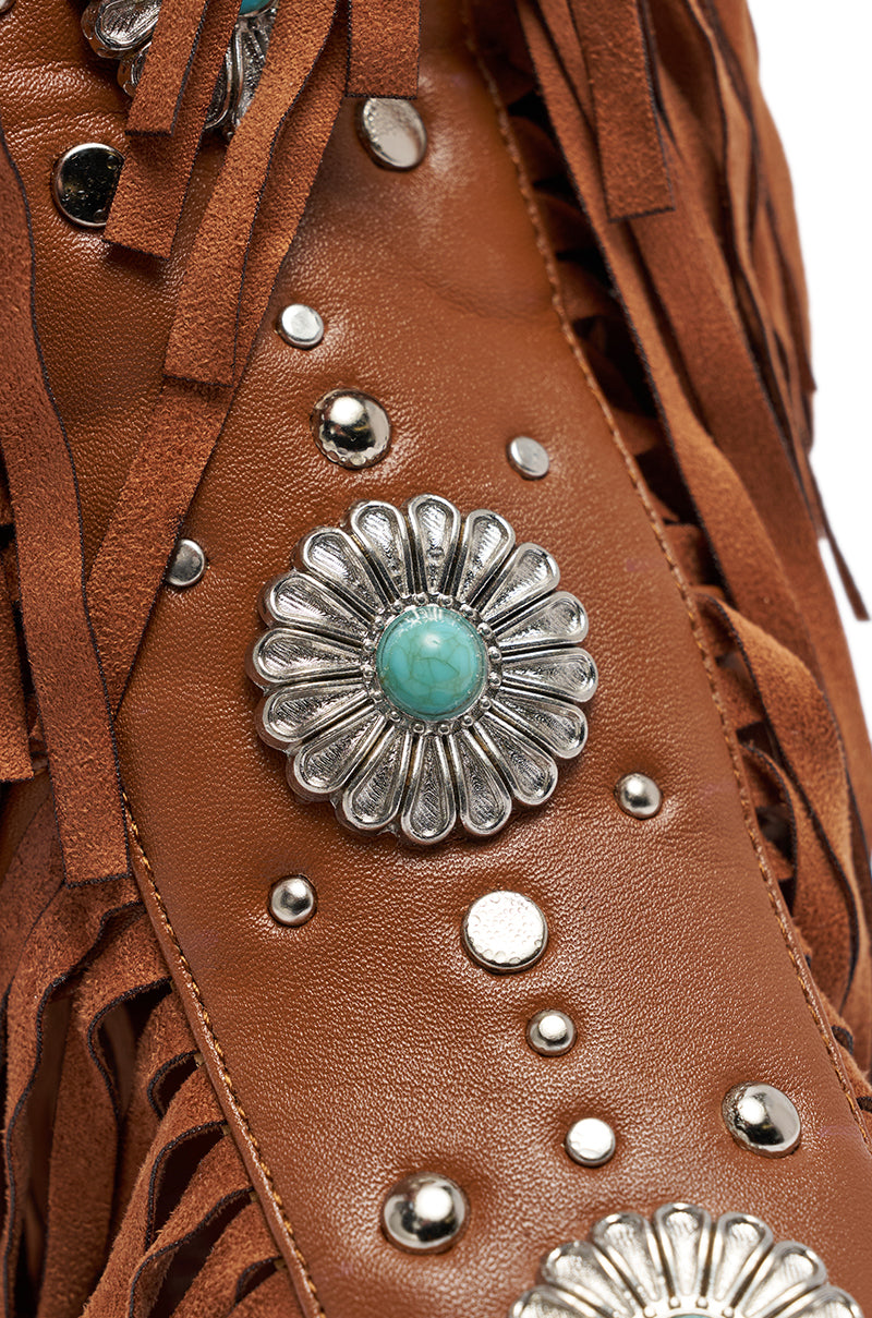 The AZALEA WANG DUSTINE BROWN GLADIATOR EMBELLISHED SANDAL features brown leather, silver studs, a turquoise stone in a floral concho, and leather fringe accents. 7