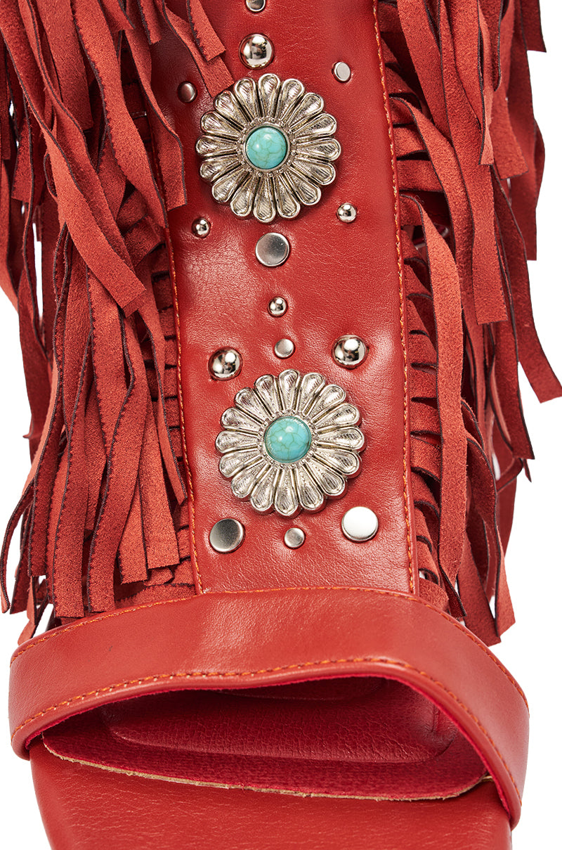Close-up of the AZALEA WANG DUSTINE RED MULTI GLADIATOR EMBELLISHED SANDAL, featuring red leather, fringe details, silver studs, two floral metal accents with turquoise centers, and an open toe design. 6