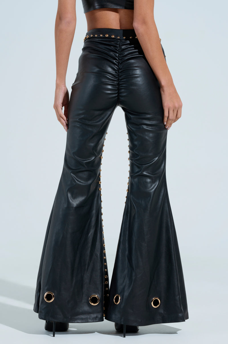 A person is wearing DW Studded Flare Pants with metallic studs, grommets, a ruched back design, and metal details at the hems against a plain light background.