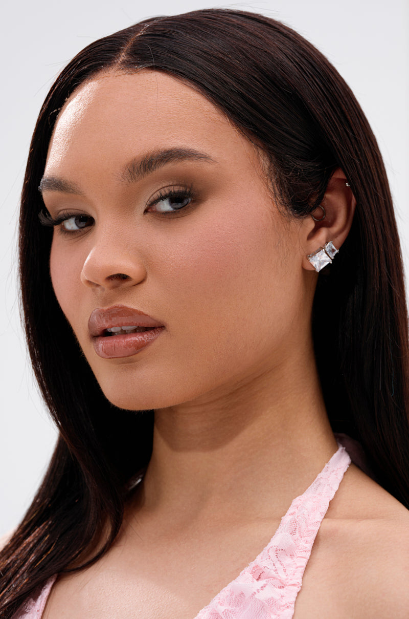 A woman with long, straight dark hair wears a light pink lace top and the 3 PACK STUD EARRING set, featuring clear crystal finishes, looking confidently at the camera against a plain background. 1