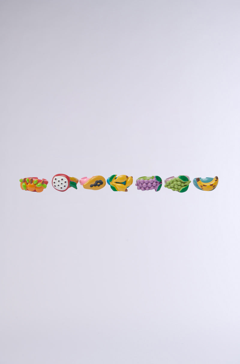 Seven illustrated fruit halves—apple, dragon fruit, papaya, mango, grapes, green grapes, and banana—line up against a light gray background, creating a playful design that inspires the vibrant THATS BANANAS RING SET.