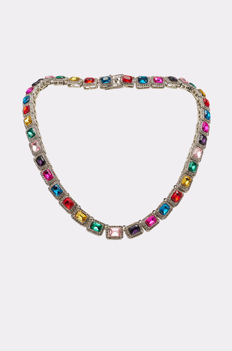 The HOW I MOVE NECKLACE is a silver tennis-chain necklace featuring evenly spaced, square-cut multicolored gemstones, shown on a plain white background. 1