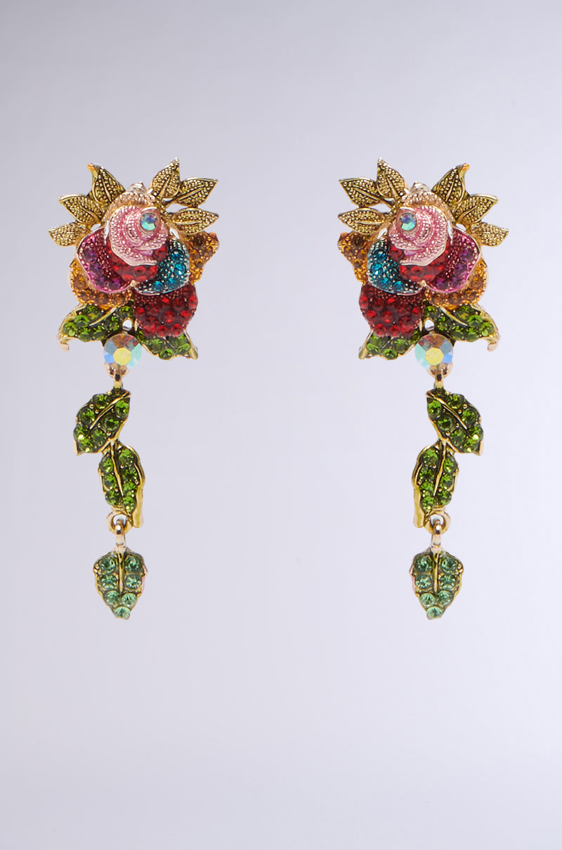 The SUMMER GARDEN DANGLE EARRING showcases ornate pink, green, and blue flower-shaped crystals with faux gold rhinestone leaves. Its cascading design of connected leaves and crystals creates a stunning dangling effect, set against a plain background. 1
