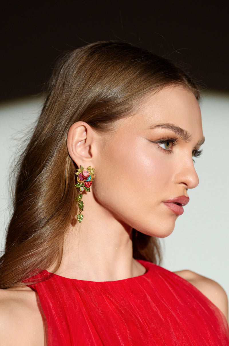 A person with long brown hair wears vibrant SUMMER GARDEN DANGLE EARRINGs featuring rhinestones and a red sleeveless top. In profile, their sophisticated makeup and smooth hair glisten in direct, soft lighting. 3