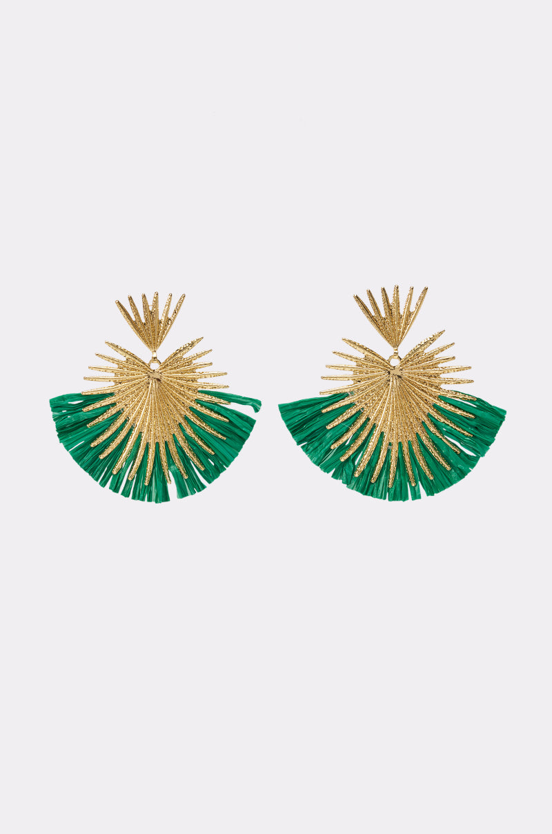 Introducing the DRESSED UP EARRING: Gold-tone earrings with sunburst designs, featuring textured rays and green fringes along the bottom edge. These striking statement pieces are ideal for resort wear, adding a playful twist to any vacation look. Displayed on a plain white background.