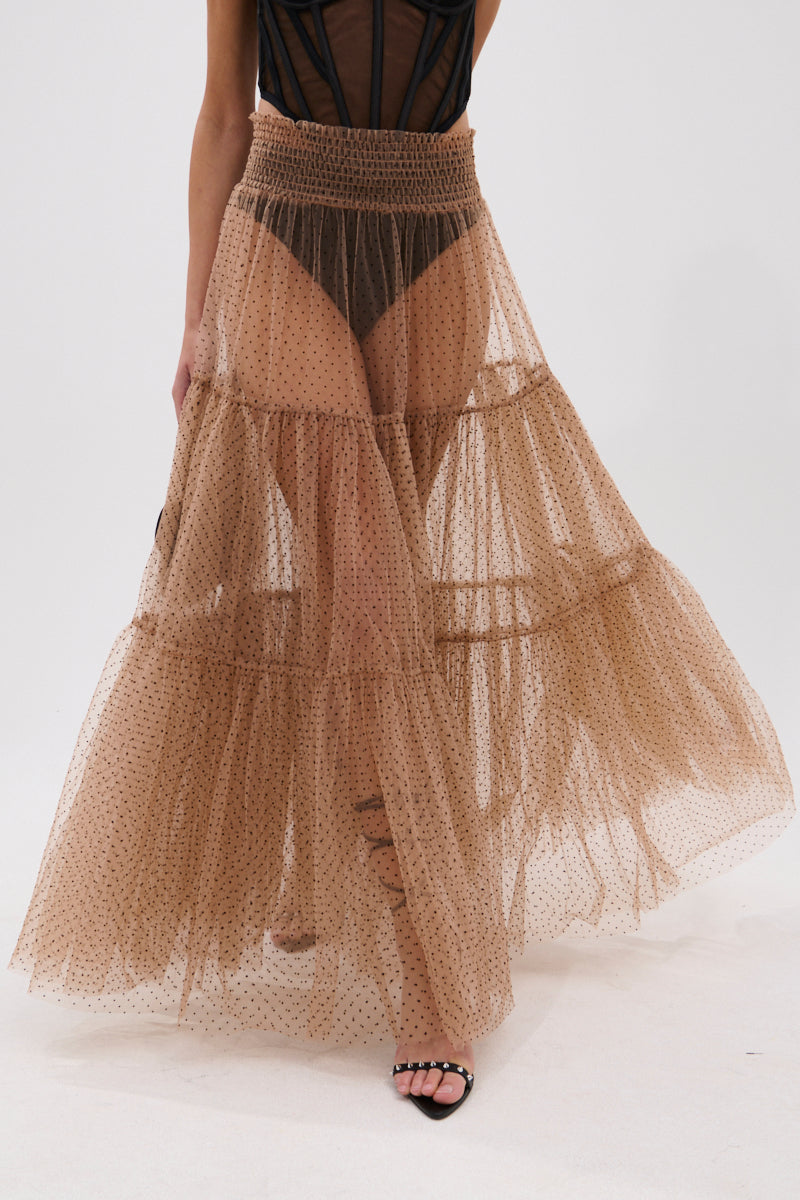 A person wears the CLASSY POLKA DOT MAXI SKIRT—sheer, tiered tan organza with velvet polka dots—over black underwear and a black top, paired with black strappy sandals against a plain white background. 2