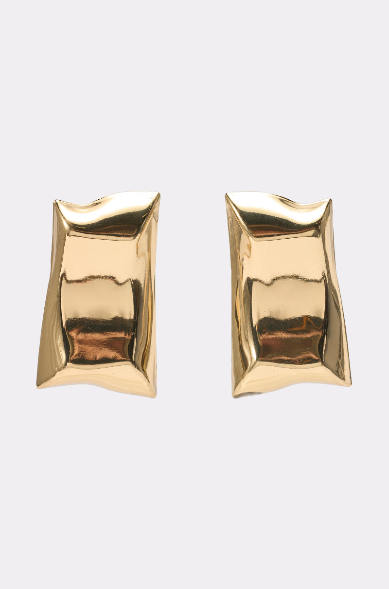 The PILLOW VIBES EARRING is a pair of shiny, gold, square-shaped stud earrings with a unique crumpled pillow-like texture, shown against a plain light background. 2