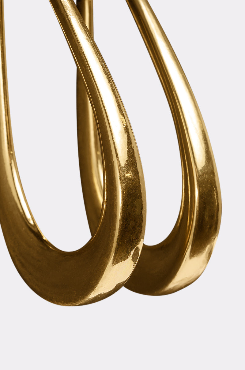 Close-up of two shiny BELLE EARRING gold teardrop earrings with smooth, curved surfaces, placed side by side against a plain light background. 4
