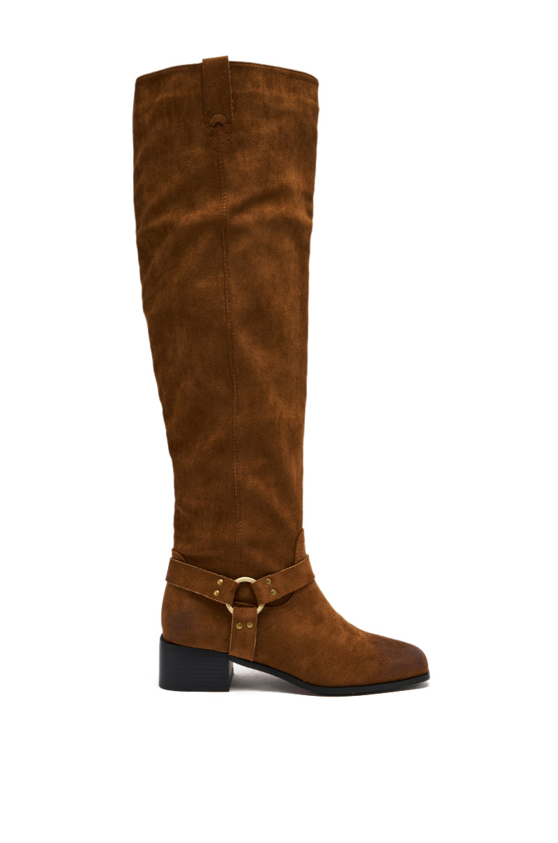 The AZALEA WANG FLAT OVER THE KNEE RIDING BOOT is a tall brown faux suede boot with a low block heel, decorative strap, and gold-tone hardware at the ankle, shown from the side against a white background.
