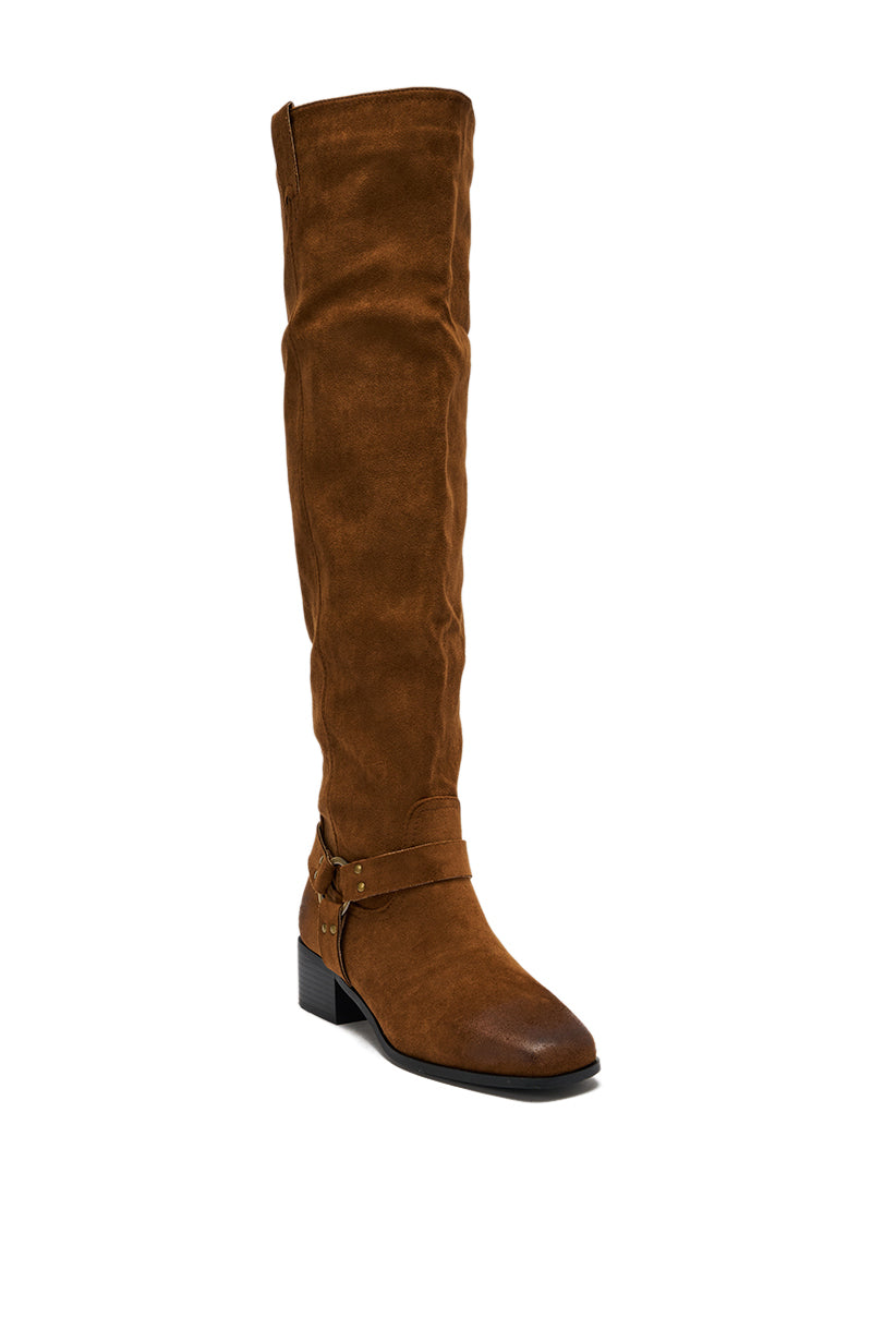 The AZALEA WANG FLAT OVER THE KNEE RIDING BOOT features brown faux suede, a low block heel, and ankle strap detail, displayed against a plain white background.