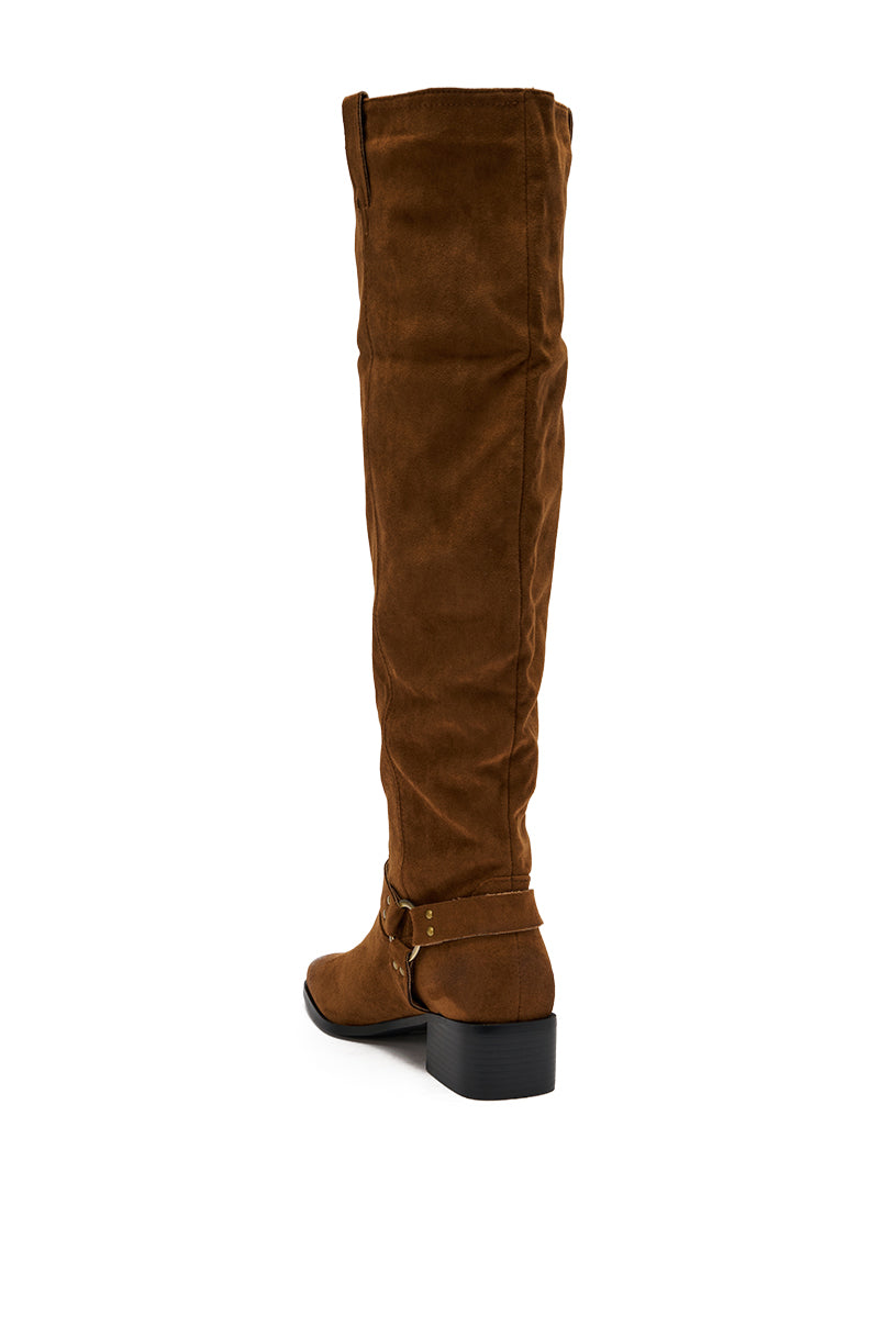 The AZALEA WANG FLAT OVER THE KNEE RIDING BOOT is a brown faux suede, over-the-knee boot with a low block heel and an ankle strap detail, displayed from the rear side on a white background.
