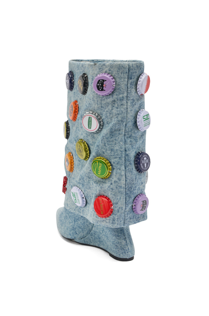 The AZALEA WANG EAVEN WEDGE EMBELLISHED DENIM BOOTIE is a light blue wedge heel bootie, decorated with colorful bottle caps, shown in a side view against a white background.