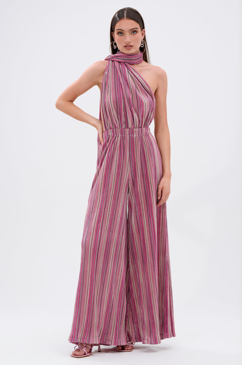A woman models the JUMPIN AROUND SLINKY JUMPSUIT—sleeveless with pink, purple, and white vertical stripes, wide-leg pants, a high neckline, and cinched waist—posing confidently against a plain backdrop. 5