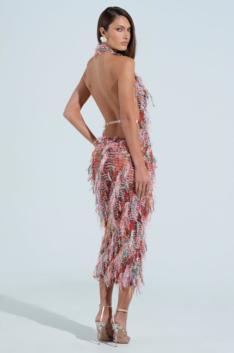 Against a plain backdrop, a woman models the vibrant SUMMER TIME LIVIN MESH MIDI DRESS IN PINK. The ruched design accentuates her curves as her long hair flows down. She looks over her shoulder, perfectly paired with high-heeled sandals.