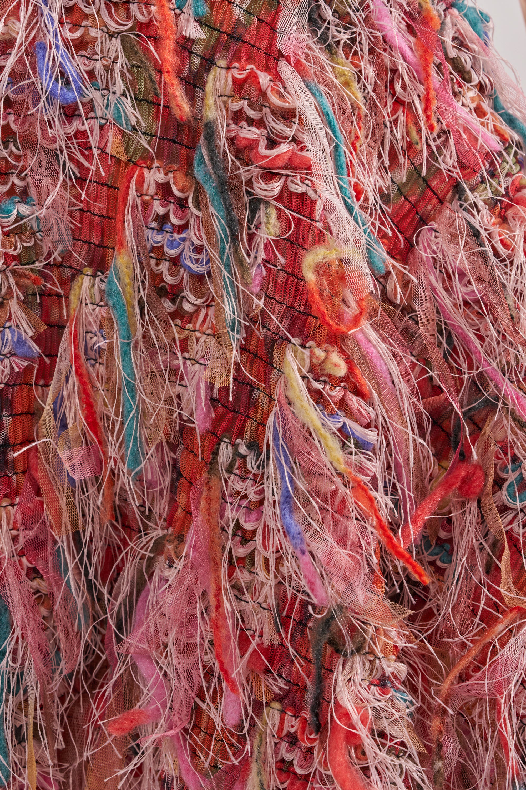 The ROMY FRINGE MESH MINI DRESS IN PINK features vibrant red, pink, yellow, and turquoise threads and fabric strips woven into layered, frayed textures that evoke the playful look of a tiered fringe mini dress. 12
