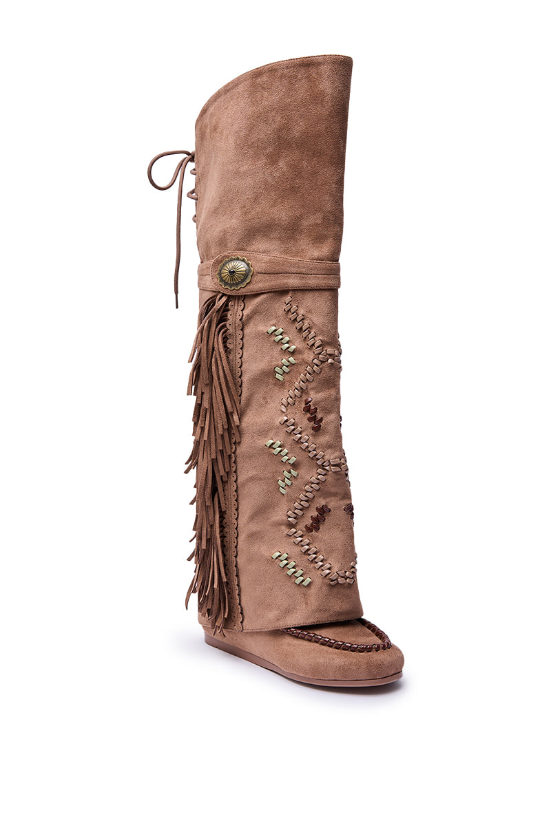 The AZALEA WANG EDMUND BROWN FLAT WESTERN BOOT features tan faux suede, fringe accents, beaded details, decorative stitching, a round bronze button, back tie, flat sole, and intricate side patterns for stylish flair.