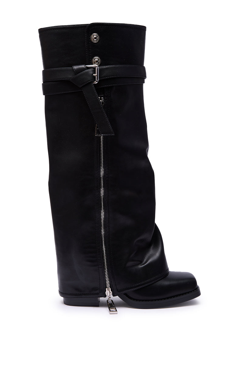 The AZALEA WANG EIRA Chunky Bootie features a black leather knee-high design with a slouched shaft, side zipper, decorative buckle strap at the top, and a square toe, photographed against a white background for edgy style.