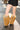 A person stands on sunlit pavement wearing black pinstripe shorts and pointy black shoes paired with AZALEA WANG EKKEN RED FOX FUR STILETTO BOOTS.