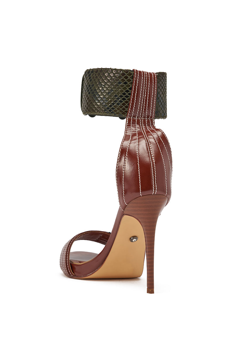The AKIRA GOLD ELEGY BROWN CROC BUCKLE HARDWARE STILETTO SANDAL features a faux leather, crocodile-embossed ankle cuff, brown base, white stitching, open toe, comfort cushion insole, slim high heel, and light tan sole. 5