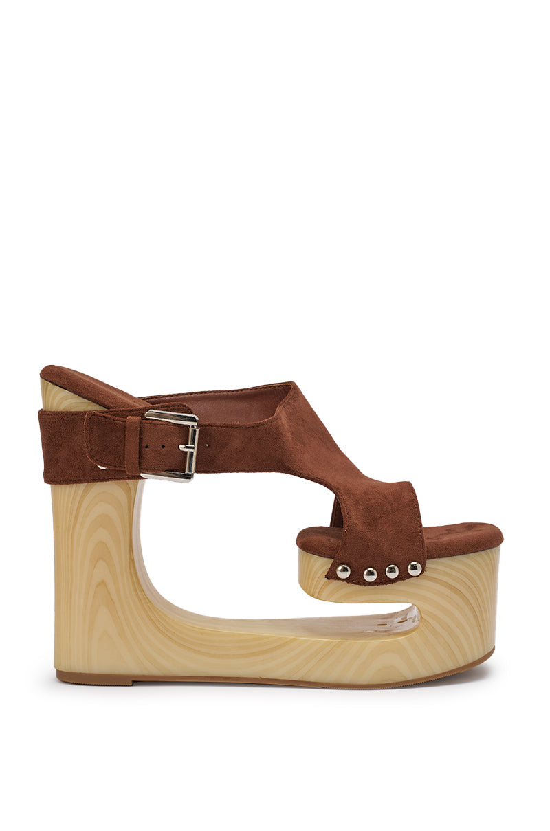 The AZALEA WANG ELGEDI TAN PLATFORM SANDAL features a brown suede upper, boho-chic style, chunky sculpted faux wood wedge heel, ankle buckle strap, and silver rivet accents by the open toe. 6