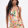 A woman with long black hair in high ponytails wears the vibrant FLOUNCE CORSET MINI DRESS featuring a strapless floral design with pleats, a fitted bodice, and a flared skirt. She stands gracefully against a plain white background.
