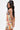 A person with long, wavy hair models the FLOUNCE CORSET MINI DRESS, featuring a vibrant mixed print, strapless neckline, fitted ruched design, and ruffled hem. They pose against a plain white background, looking over their shoulder.