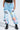 A person wears FIRST CLASS TICKET GRAPHIC CARGO RELAXED LEG JEANS, featuring graffiti-style graphics with colorful words and designs. Paired with a black top and combat boots, hands in pockets; only the lower half is shown—ideal for streetwear fans.