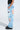 Person wears FIRST CLASS TICKET GRAPHIC CARGO RELAXED LEG JEANS in light blue with colorful graffiti graphics, phrases like “Tokyo Is My Jam” and “Eyes,” plus smiley faces, posed sideways against a plain background.