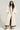A person with long curly hair is wearing the BEAR HUG REVERSIBLE FLEECE TRENCH, featuring an oversized silhouette and a hood, in cream with brown trim. They stand with one hand in their pocket and are wearing tan boots against a light-colored background.