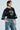 Someone confidently poses against a plain background wearing the CHAMPIONSHIP SCRUNCH JERSEY, featuring varsity-inspired stripes, the number 73, silky jersey fabric, and wide sleeves, paired with blue jeans.