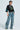 A person in a CHAMPIONSHIP SCRUNCH JERSEY with the number 73 and blue accents pairs it with baggy denim cargo pants. Varsity-inspired stripes enhance their style as they pose confidently against a plain background.