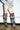 A person in frayed denim shorts and tall, slouchy AZALEA WANG ELODIE PLAID MULTI FLANNEL STILETTO BOOTS with pointed heels stands indoors against a plain wall.