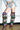 A person poses indoors in distressed denim shorts and AZALEA WANG ELODIE PLAID MULTI FLANNEL STILETTO BOOTS, the bold over-the-knee plaid boots standing out against a white wall and concrete floor.