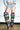 A person stands indoors on concrete, wearing distressed denim shorts, a light blue cropped jacket, and the AZALEA WANG ELODIE PLAID MULTI FLANNEL STILETTO BOOT—showcasing bold women's fall footwear.