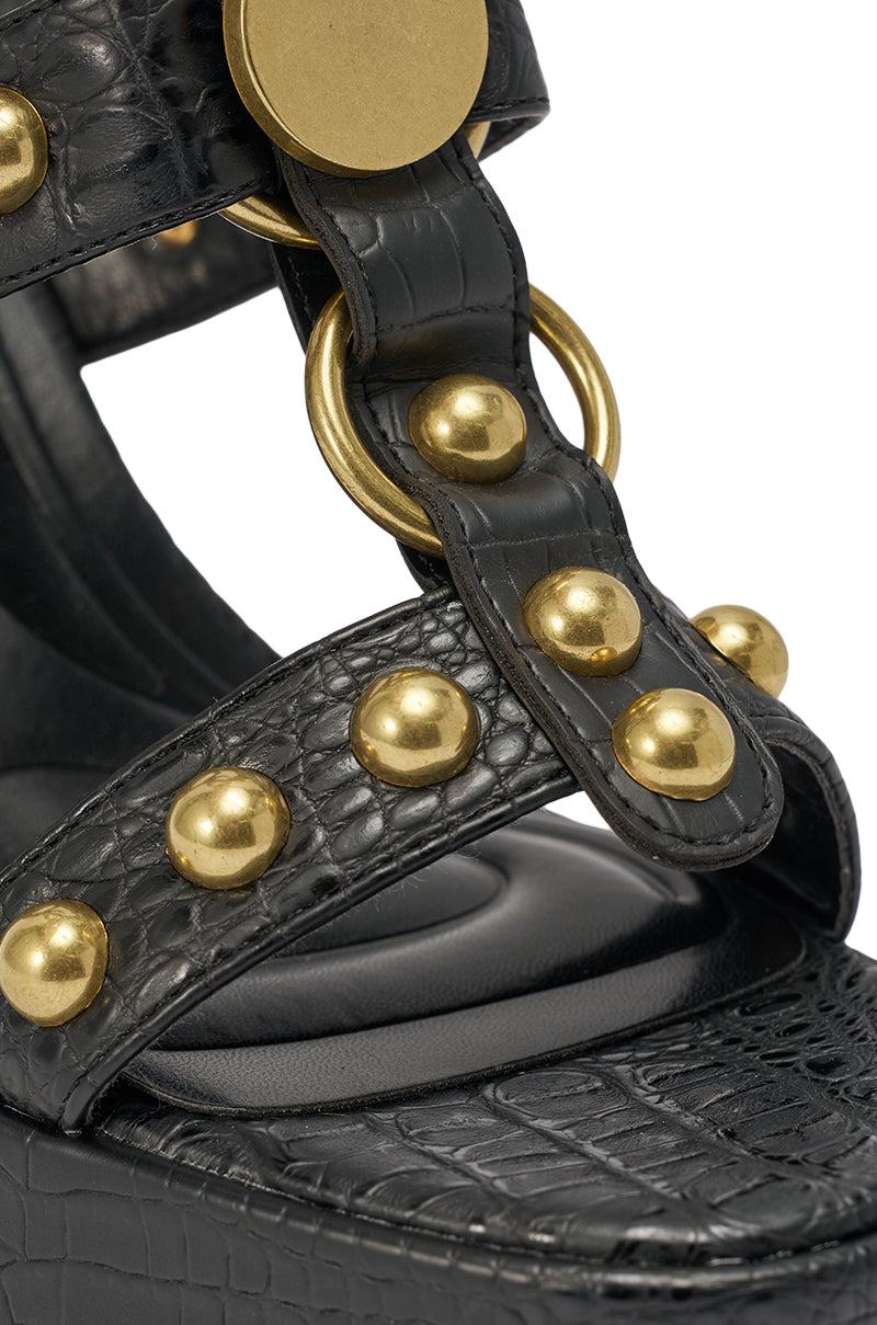 The AZALEA WANG ELSU BLACK CROC EMBOSSED PLATFORM SANDAL features thick straps, shiny gold studs and rings, a bold platform sole, and a striking black croc-embossed faux leather finish. 7