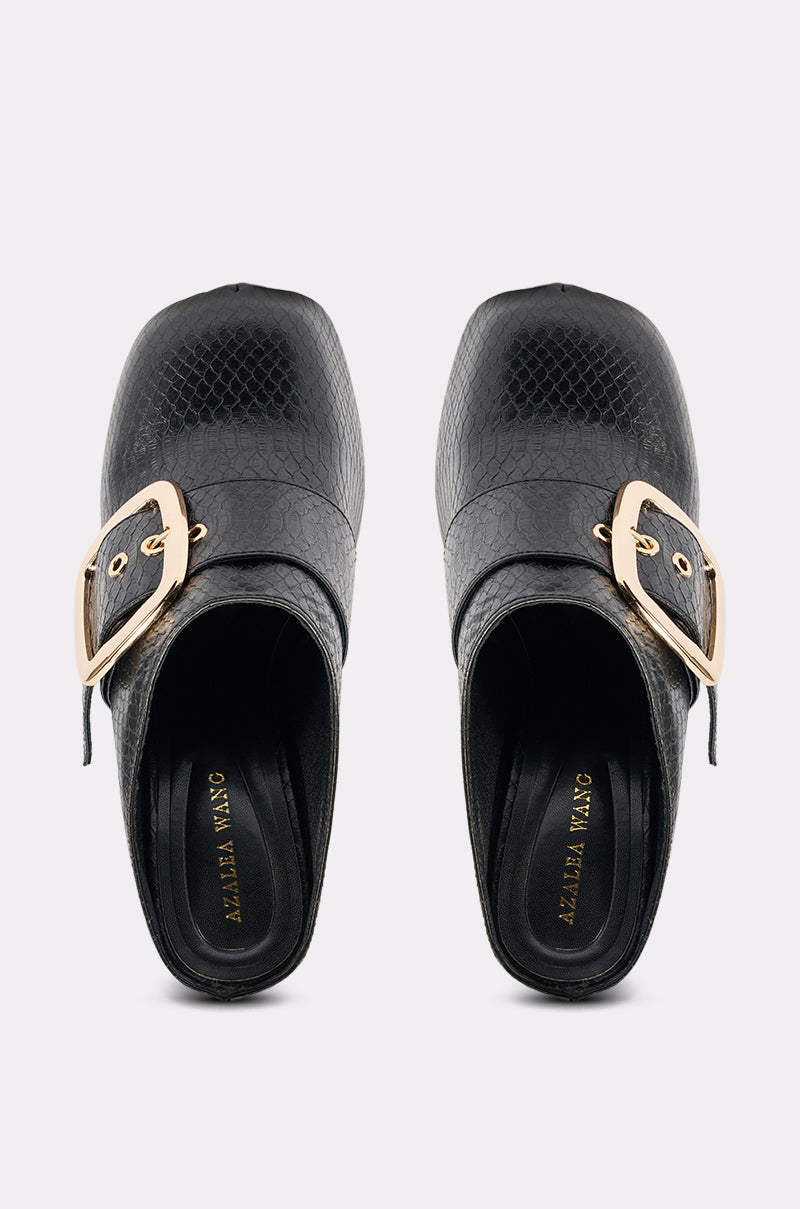 The AZALEA WANG ELYSIA BLACK PU ROUND TOE MULE features black textured faux leather, gold buckles, and a subtle chunky heel. Branded gold text decorates the insoles. Presented from above on a light gray background. 6