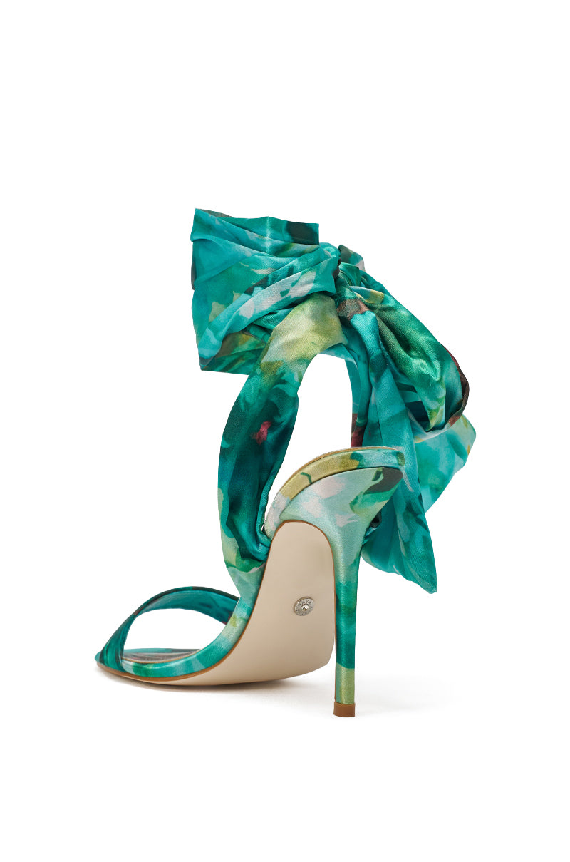 The AZALEA WANG ELZON GREEN SATIN STRAPPY SANDAL features teal, green, and white floral patterns, satin wraparound laces, an ankle bow, and a slim green stiletto heel—all set against a white background. 5