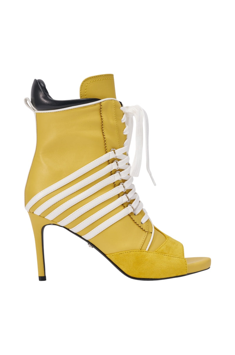 The AZALEA WANG EOWYN Mustard Yellow Open Toe Stiletto Bootie features white laces, horizontal white side straps, a black back detail, and a high-heeled ankle boot design.