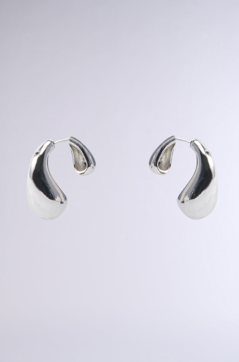 The AKIRA Label HOT GIRL EARRING features shiny, teardrop-shaped silver earrings with a smooth, organic design, shown against a light gray background.