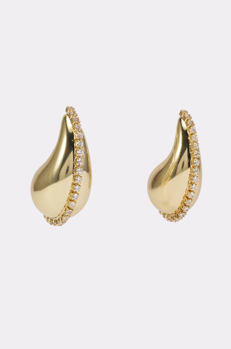 Introducing the GLAM BAE DROP STUDS: elegant gold tear drop studs featuring a curved row of sparkling rhinestones along one edge—perfect for complementing your evening wear. Presented against a plain light background.