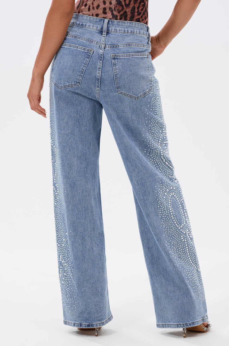 A person models the DREAMING OF YOU WIDE LEG DENIM—high-rise, light blue wide-leg jeans with back pockets and decorative rhinestone patterns on the sides—against a plain white background. 4