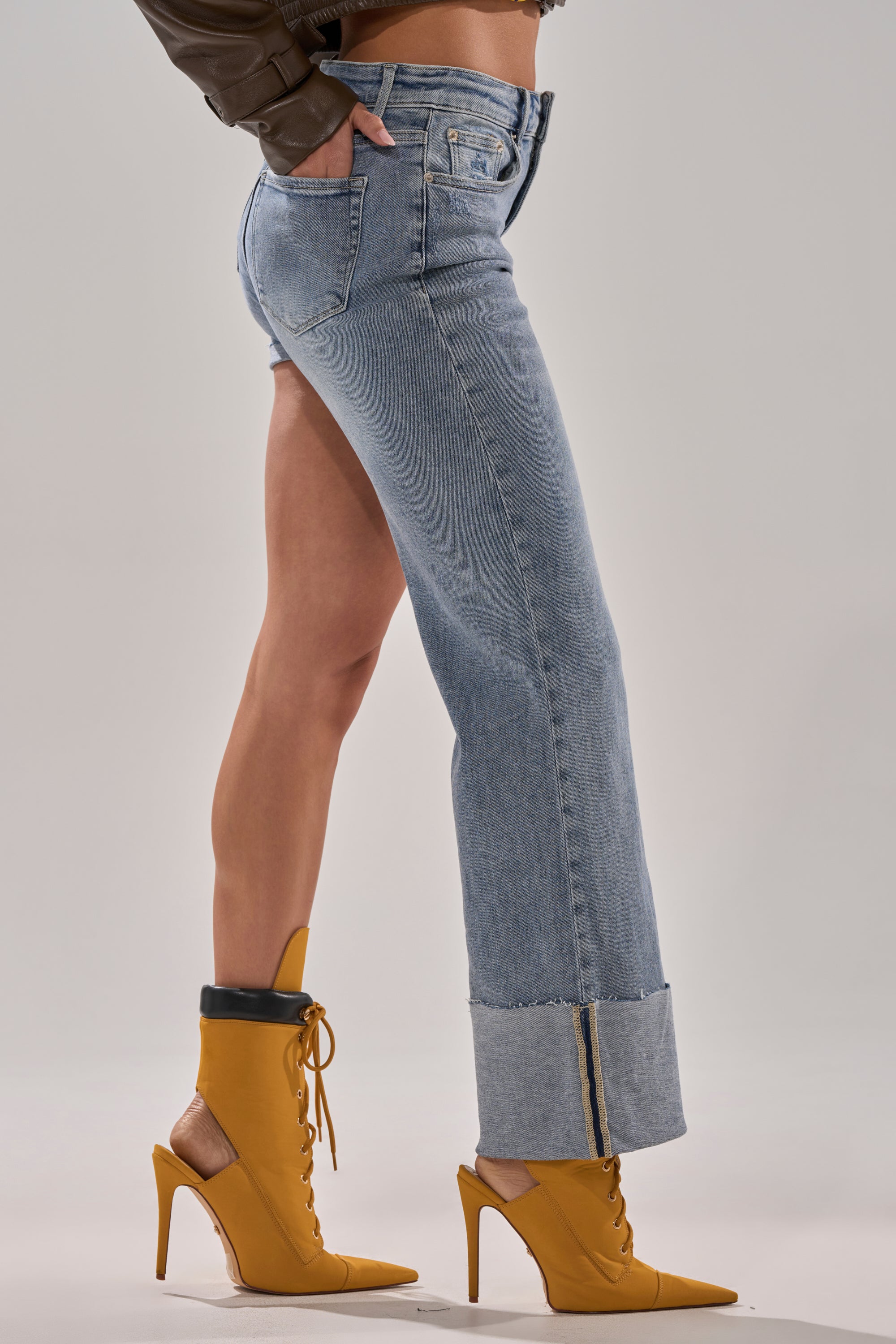 Wearing BOTH SIDES OF ME DENIM—light-wash jeans with ankle zippers—paired with mustard yellow lace-up high-heeled shoes, only the lower body and legs are shown against a plain backdrop.