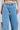 Close-up of a person wearing TAKE ME OUT RHINESTONE DENIM JEANS, featuring sparkling silver rhinestones in a diamond pattern. These high-rise straight-leg jeans are styled with a glittery silver belt and matching handbag.