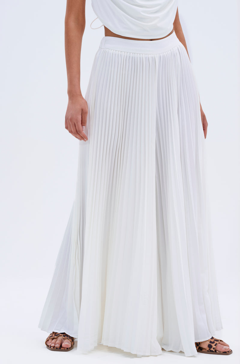 A person models the FLY INTO THE AIR PALAZZO PANT in white with a matching top and flat, open-toed sandals, standing against a plain white background.